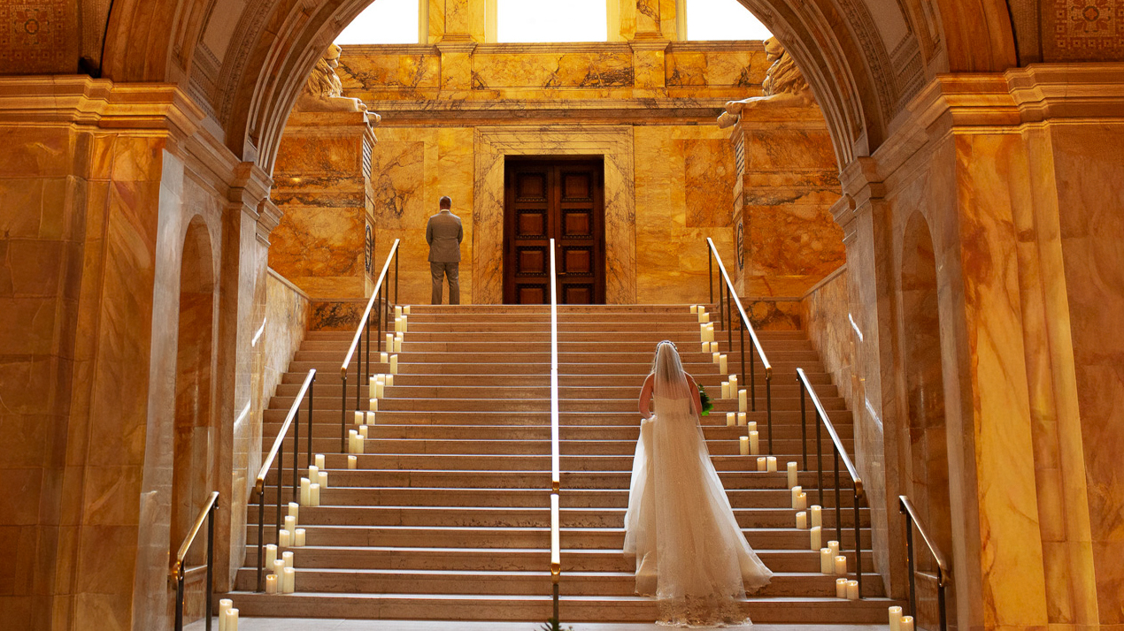 Boston Winter Weddings: 12 Reasons For A Snow-Dusted Celebration 1 A bride climbs a candlelit marble staircase as her groom waits at the top