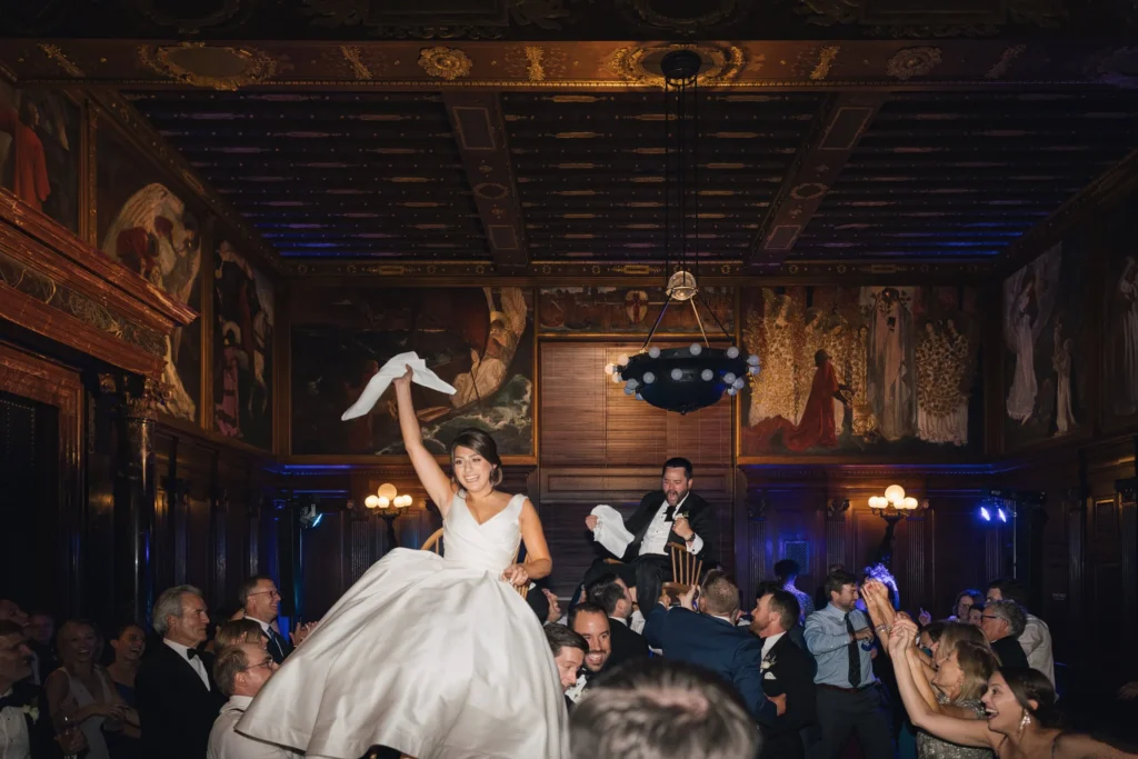 Bride dances with her veil raised beneath the murals of the Boston Public Library
