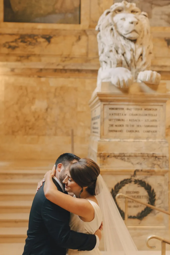 Bride and groom kiss beside the carved stone lion on the Boston Public Library staircase