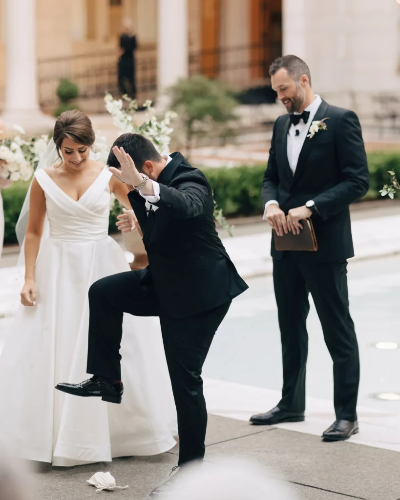 Groom adjusts his shoe in the Boston Public Library courtyard