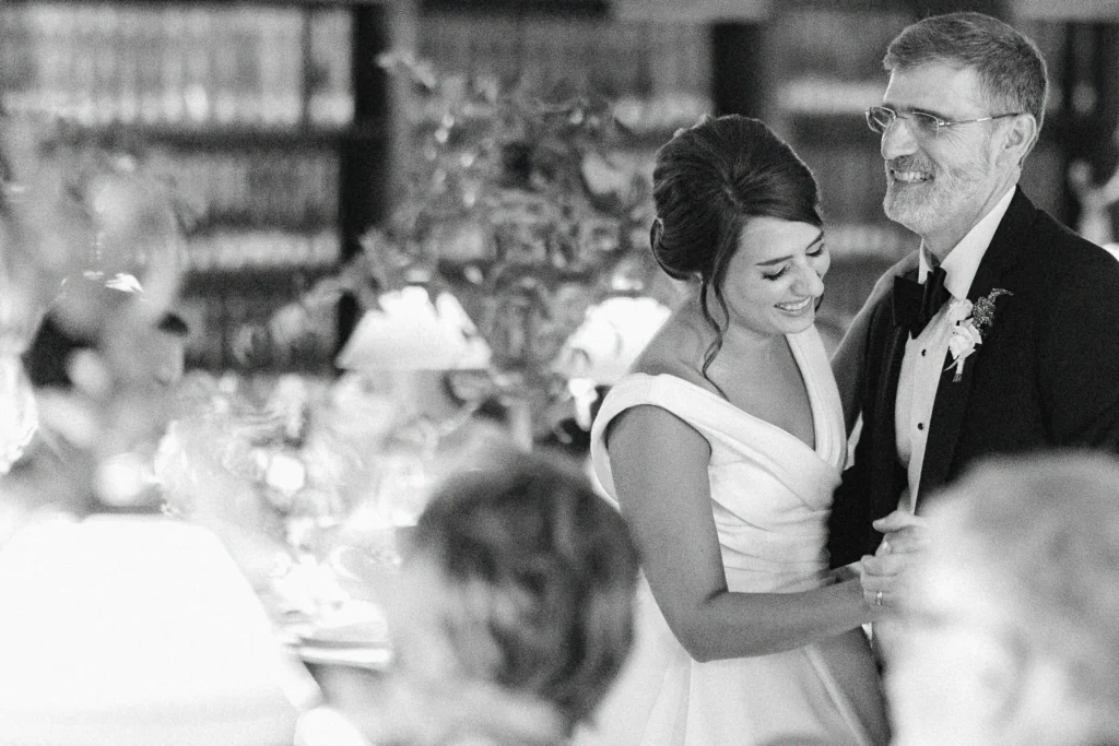 Bride laughs with her father during dinner at the Boston Public Library, black and white