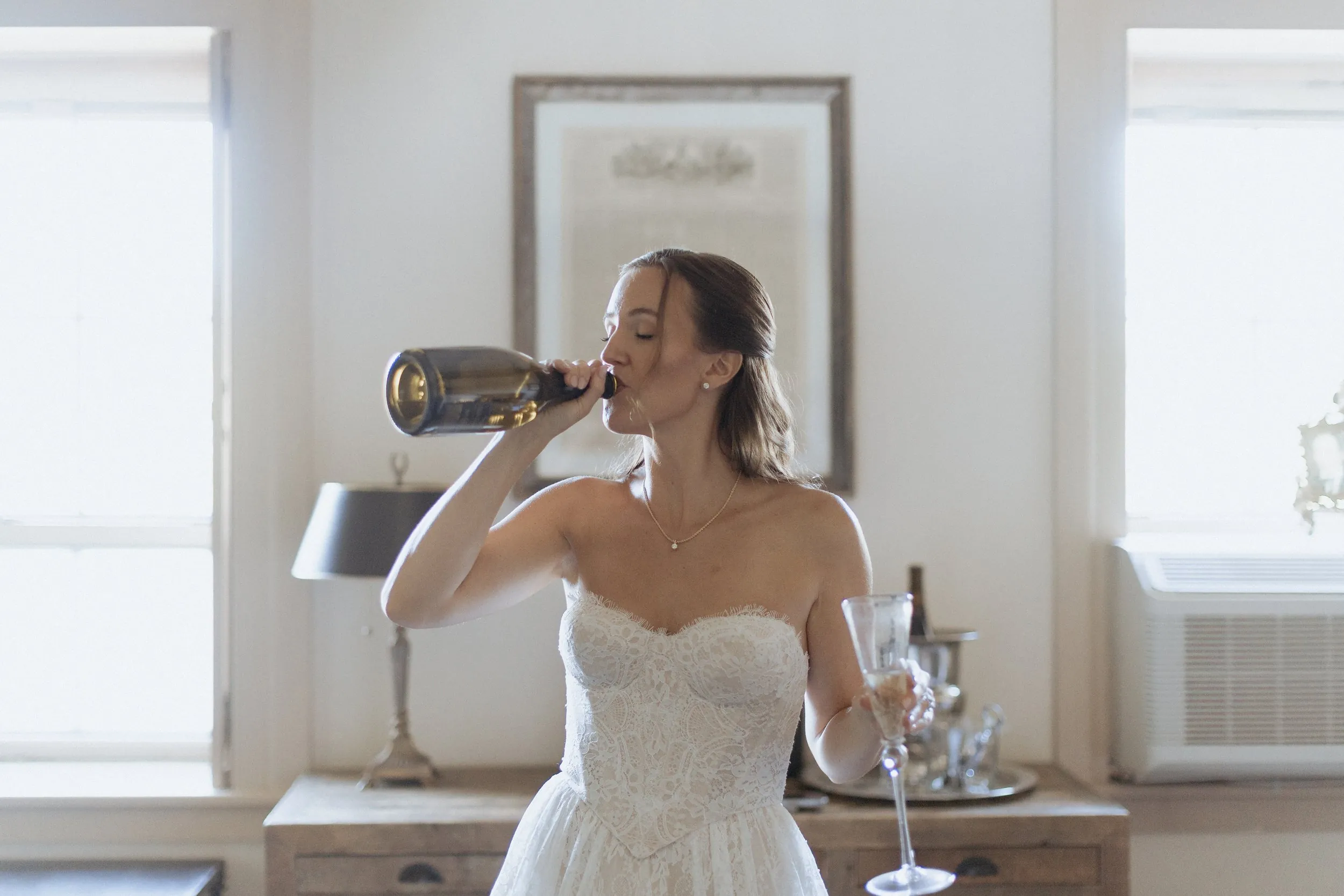 Bride drinking from a champagne bottle in her wedding dress at the Garrison Inn