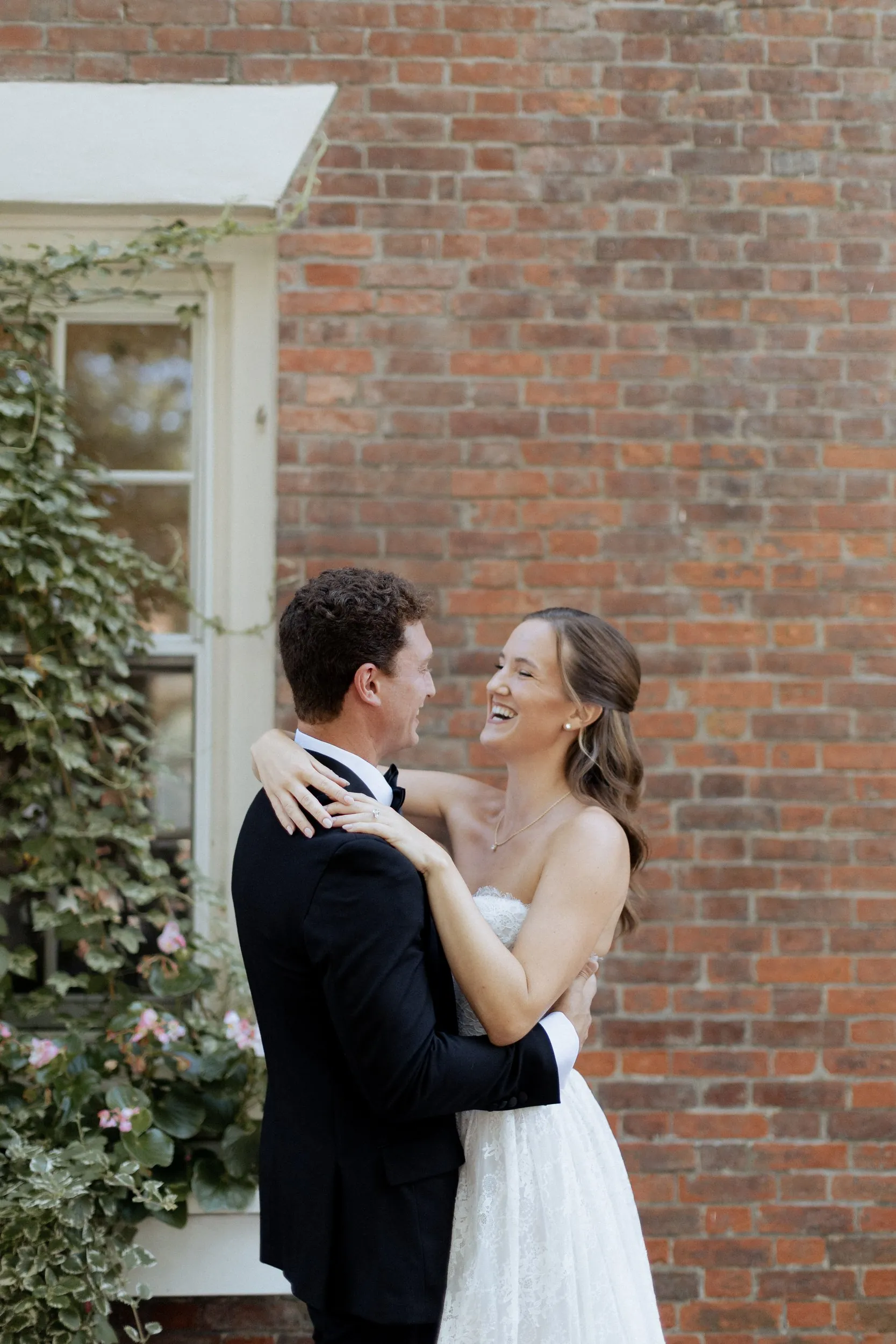 Couple embracing against the brick wall of the Garrison Inn after their first look