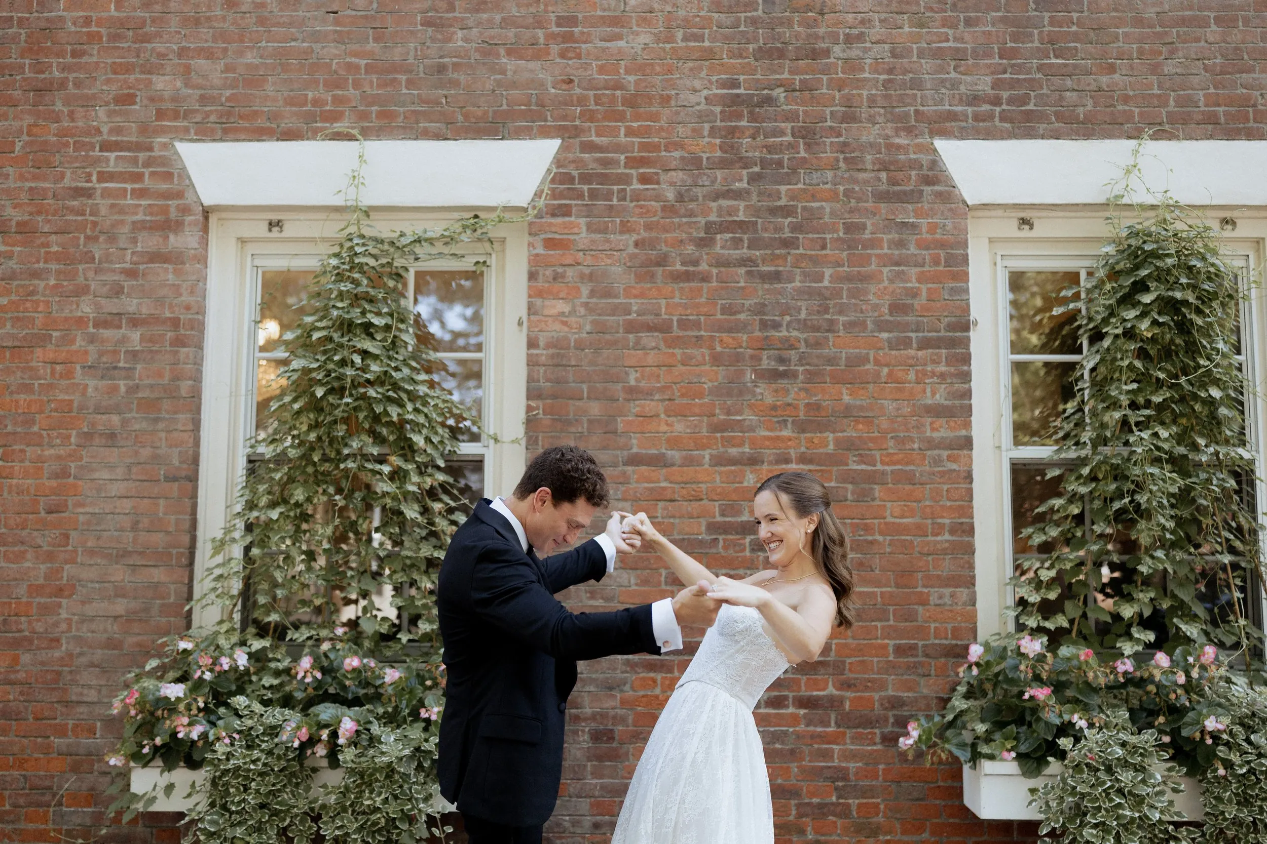 Groom twirling the bride outside the Garrison Inn before their Crane Estate wedding