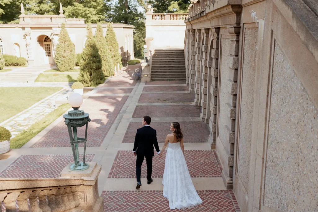 Bride and groom walking hand in hand along the stone terrace beside the Great House at the Crane Estate before their ceremony