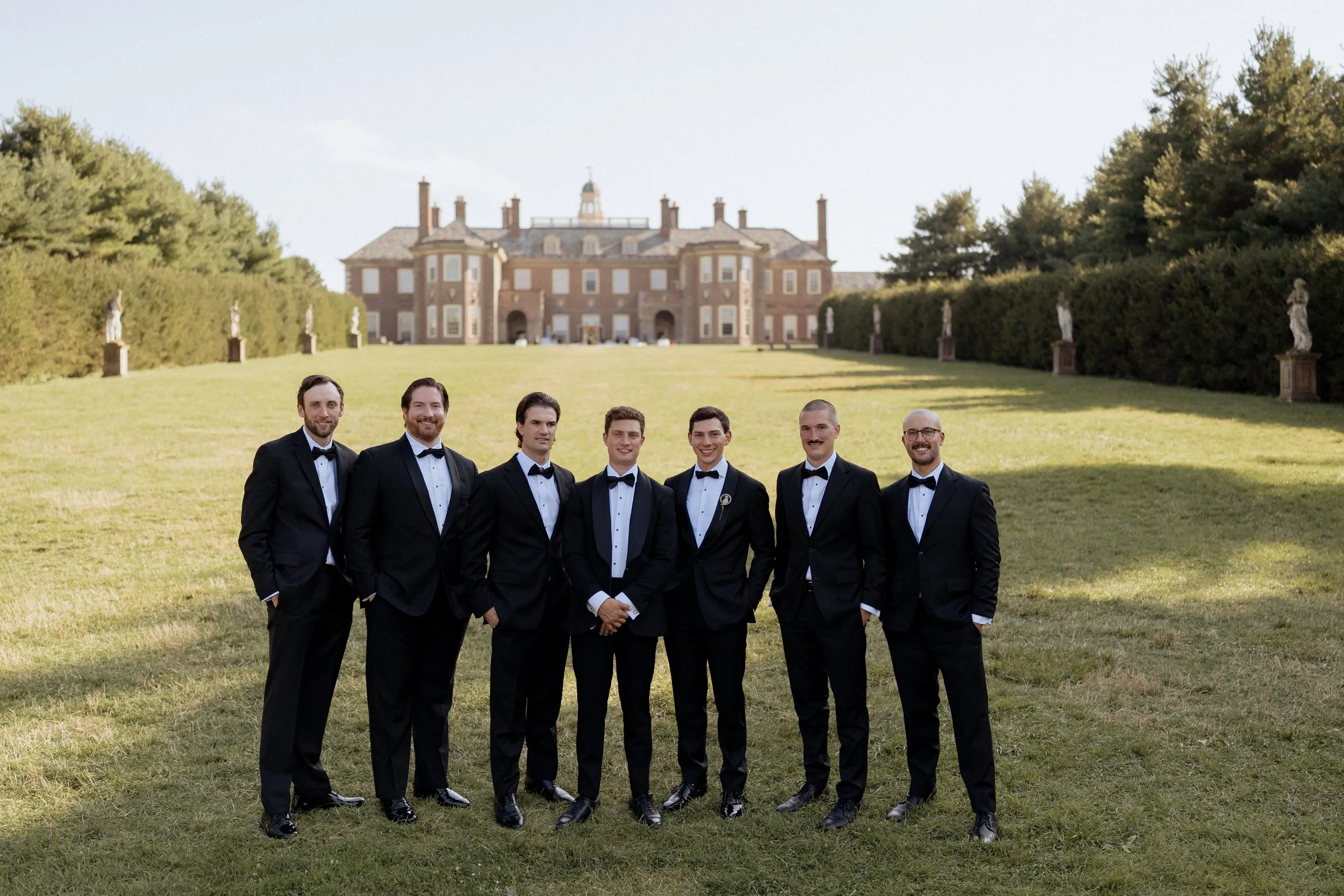 Groomsmen in black tie on the Grand All&eacute;e in front of the Great House