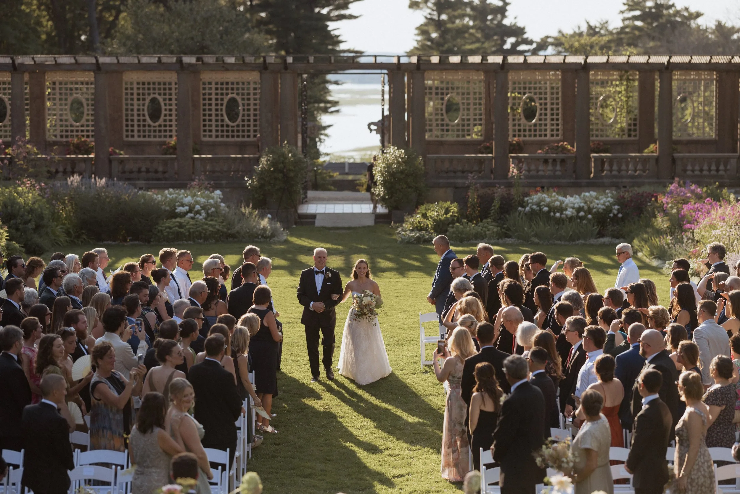 Guests standing as the bride and her father walk down the aisle at Castle Hill