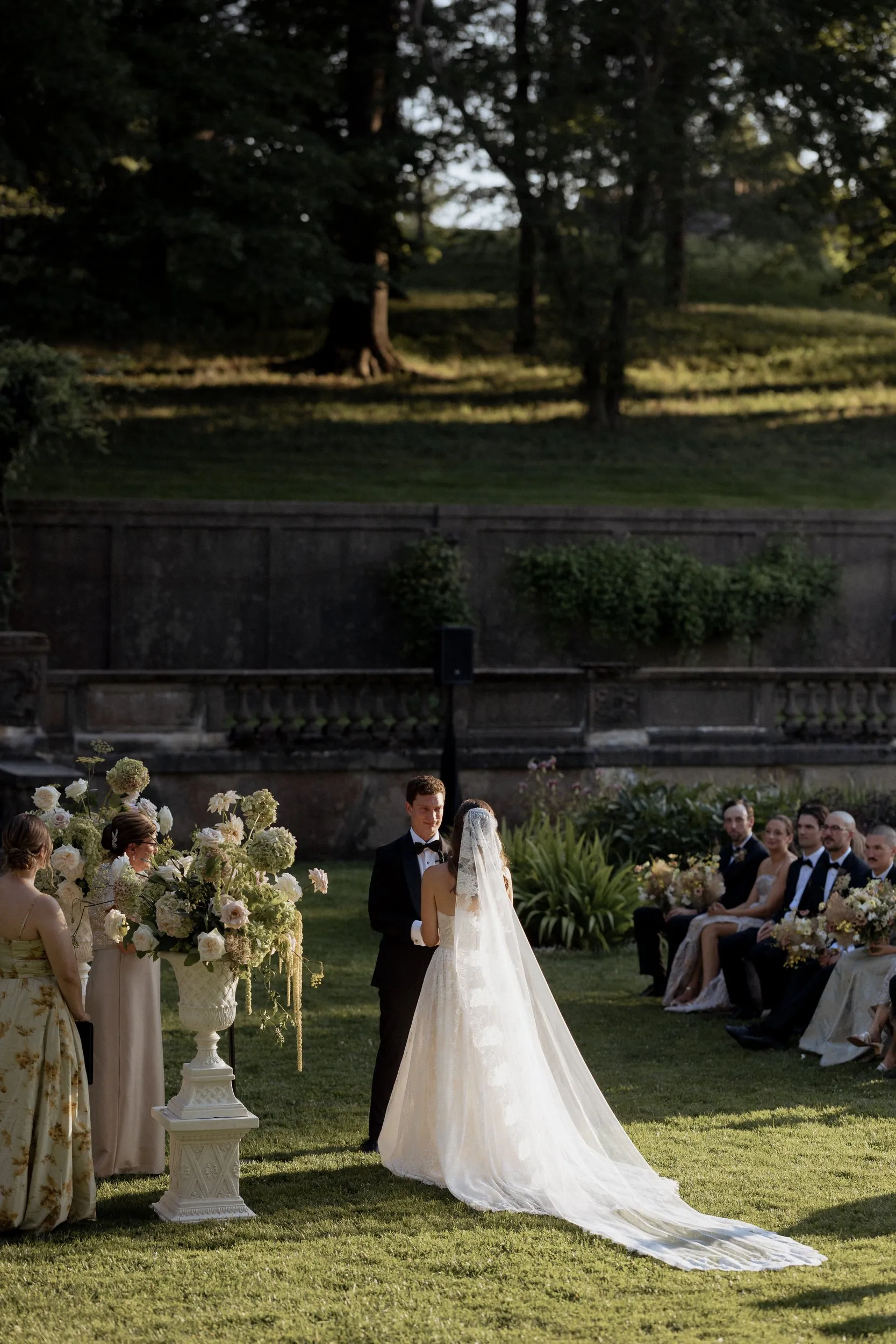Bride in a cathedral veil facing the groom during vows in the Italian Garden