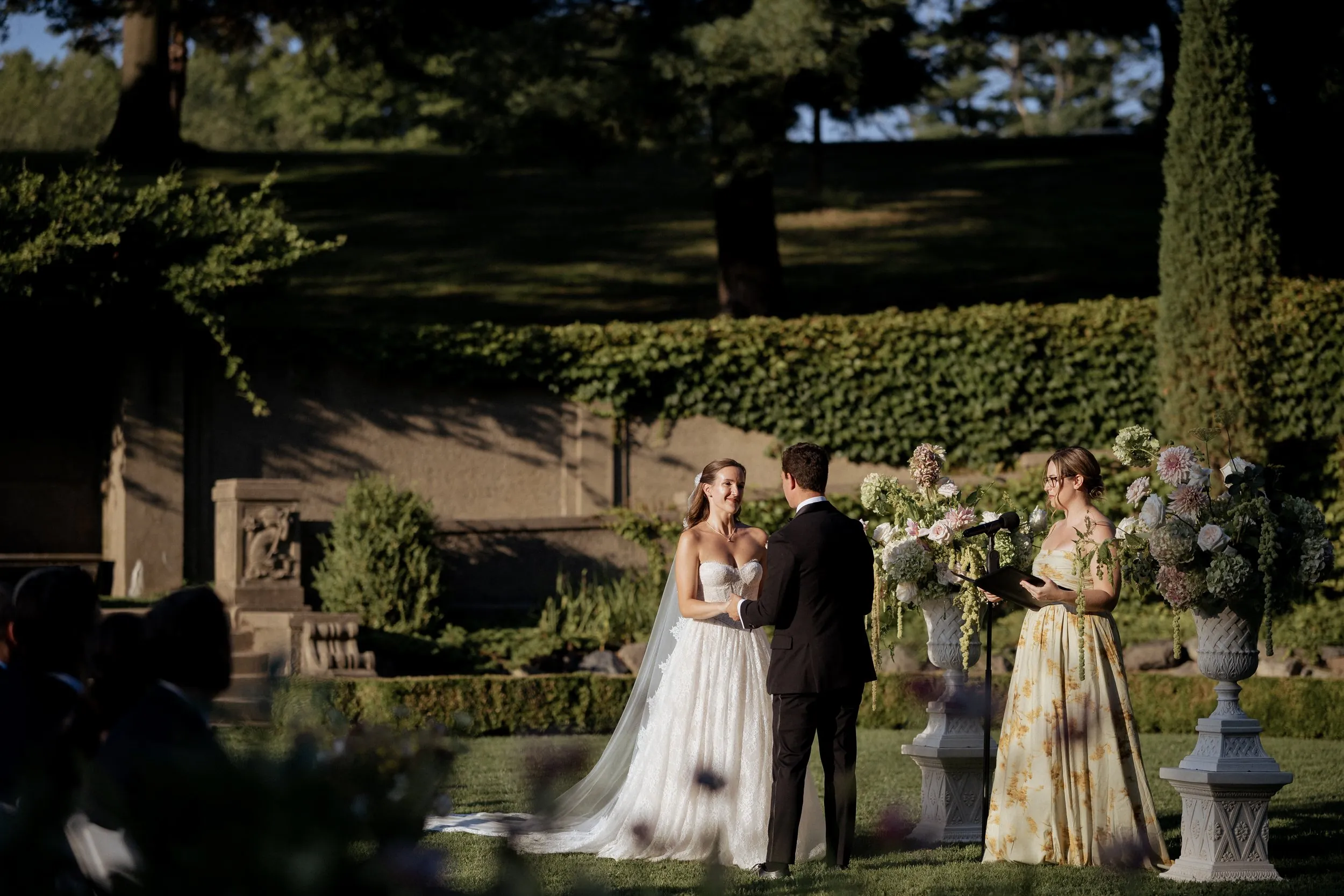 Couple exchanging rings in front of the ivy-covered garden wall at the Crane Estate