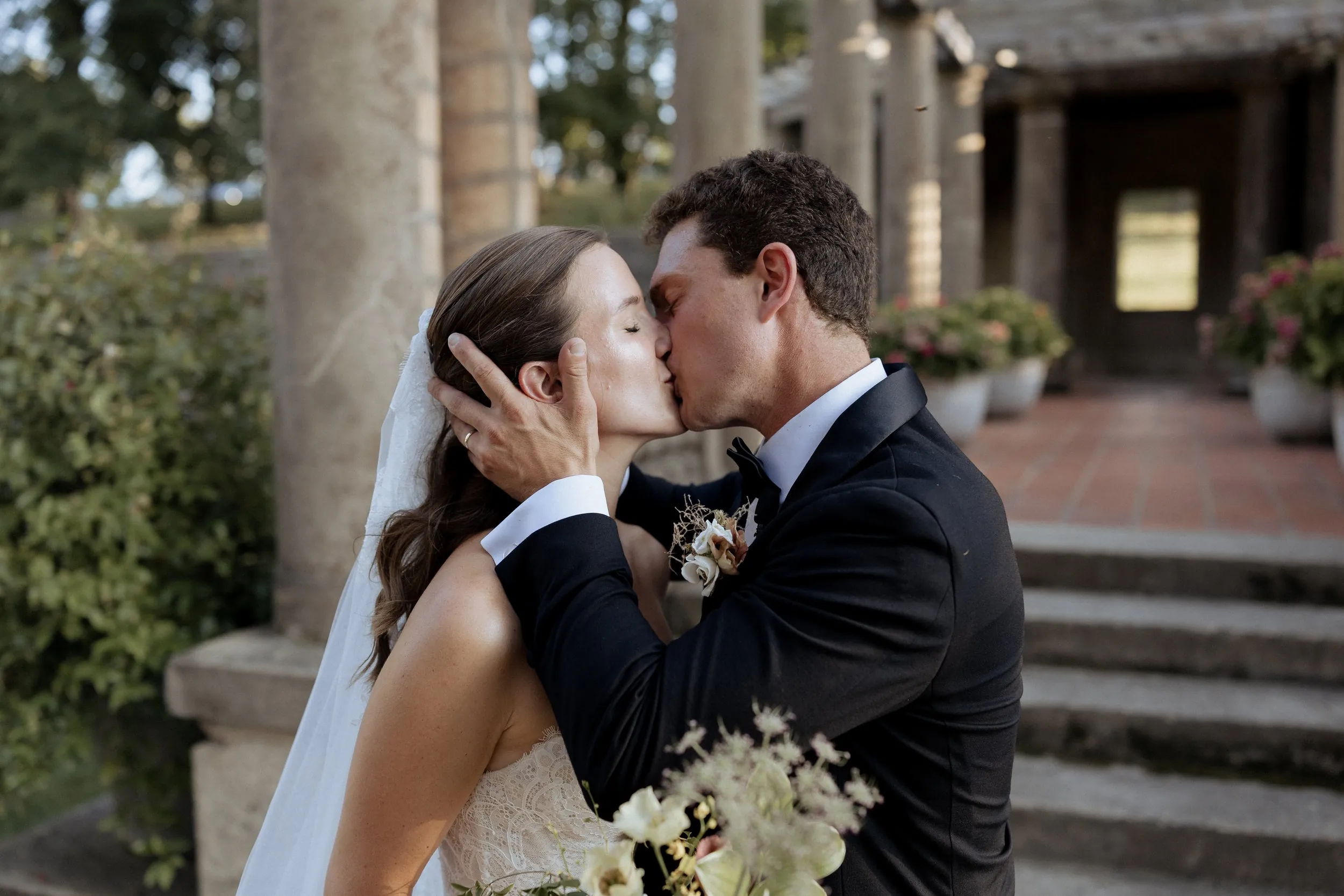 Bride and groom kissing under the pergola after their Crane Estate ceremony
