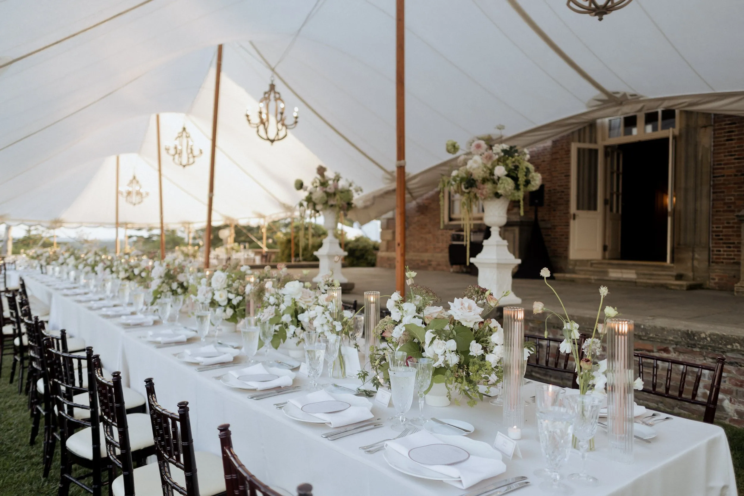 Head table with low flowers and taper candles beside the Great House