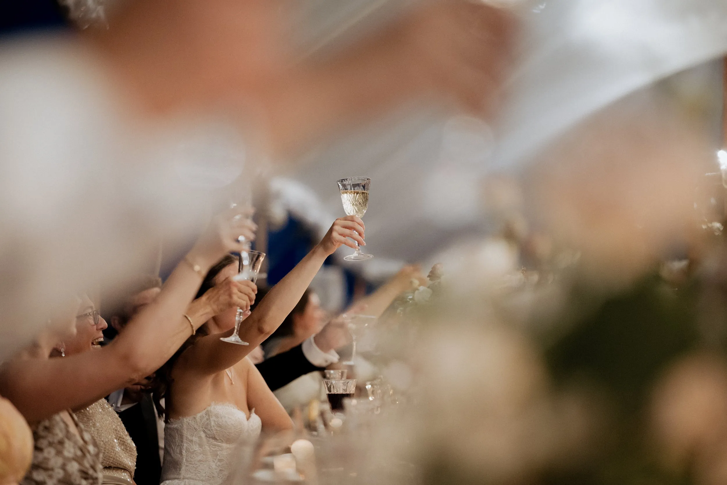 Guests toasting the couple under the sailcloth tent at night