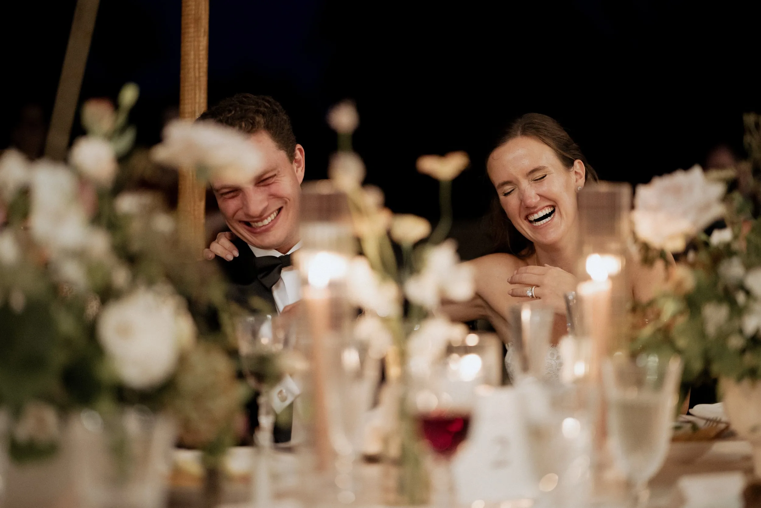 Bride and groom laughing together during the best man's speech
