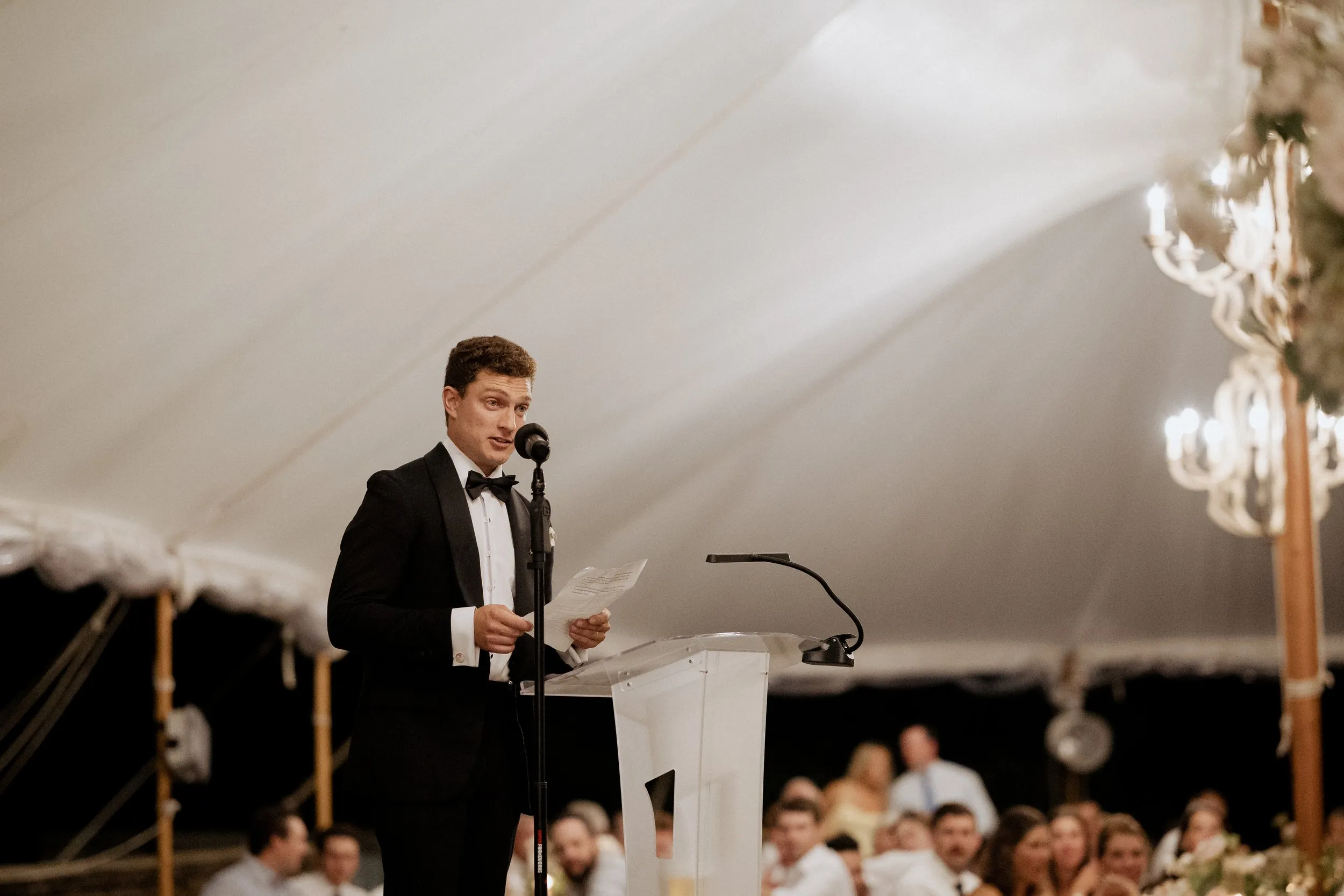 Groom giving his speech at the microphone under the tent