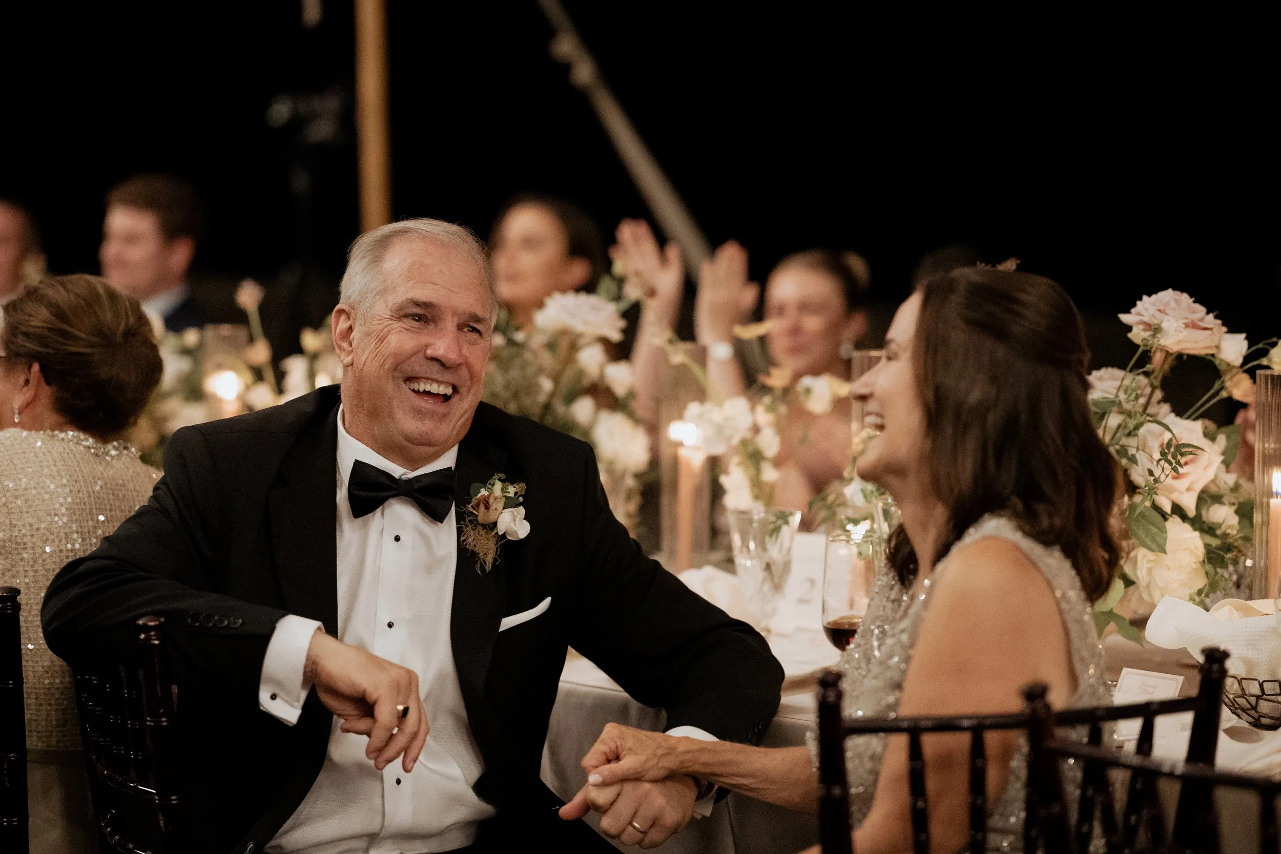 Father of the bride laughing at the table during the groom's speech
