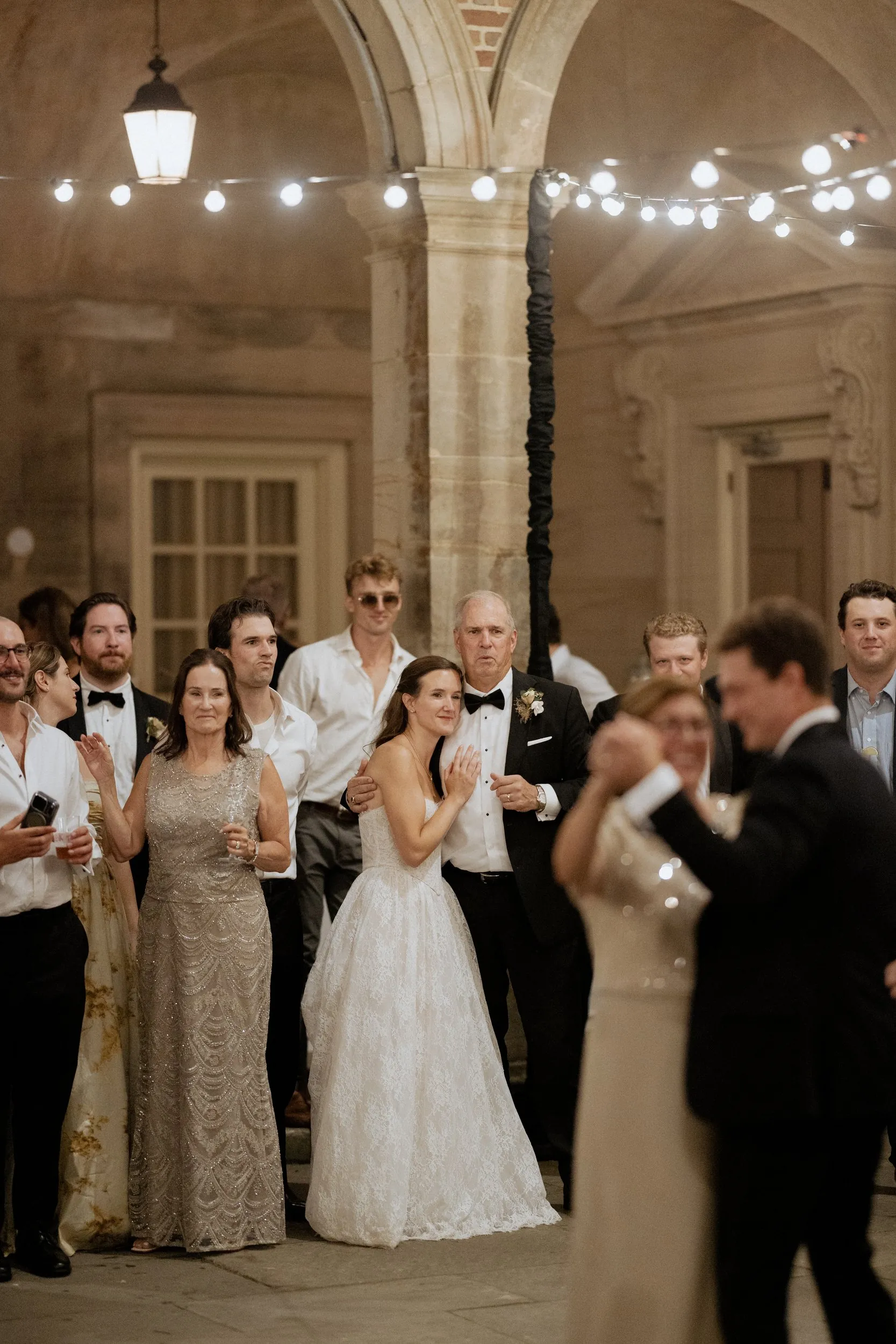 Groom dancing with his mother while guests look on in the courtyard