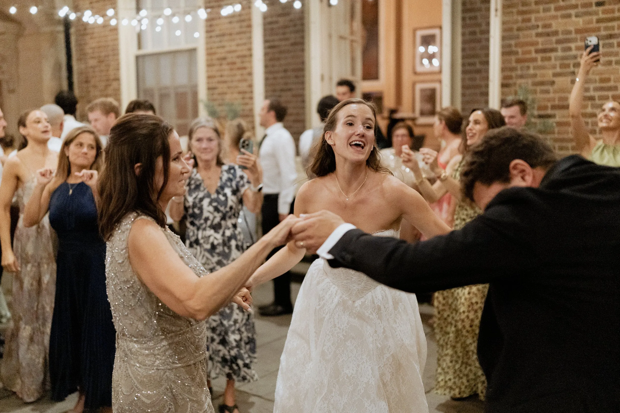 Bride dancing with guests in the courtyard under string lights