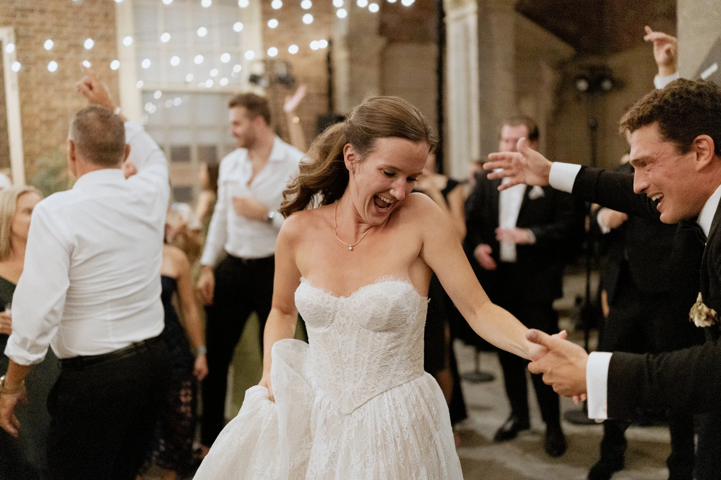 Bride laughing on the dance floor with her friends