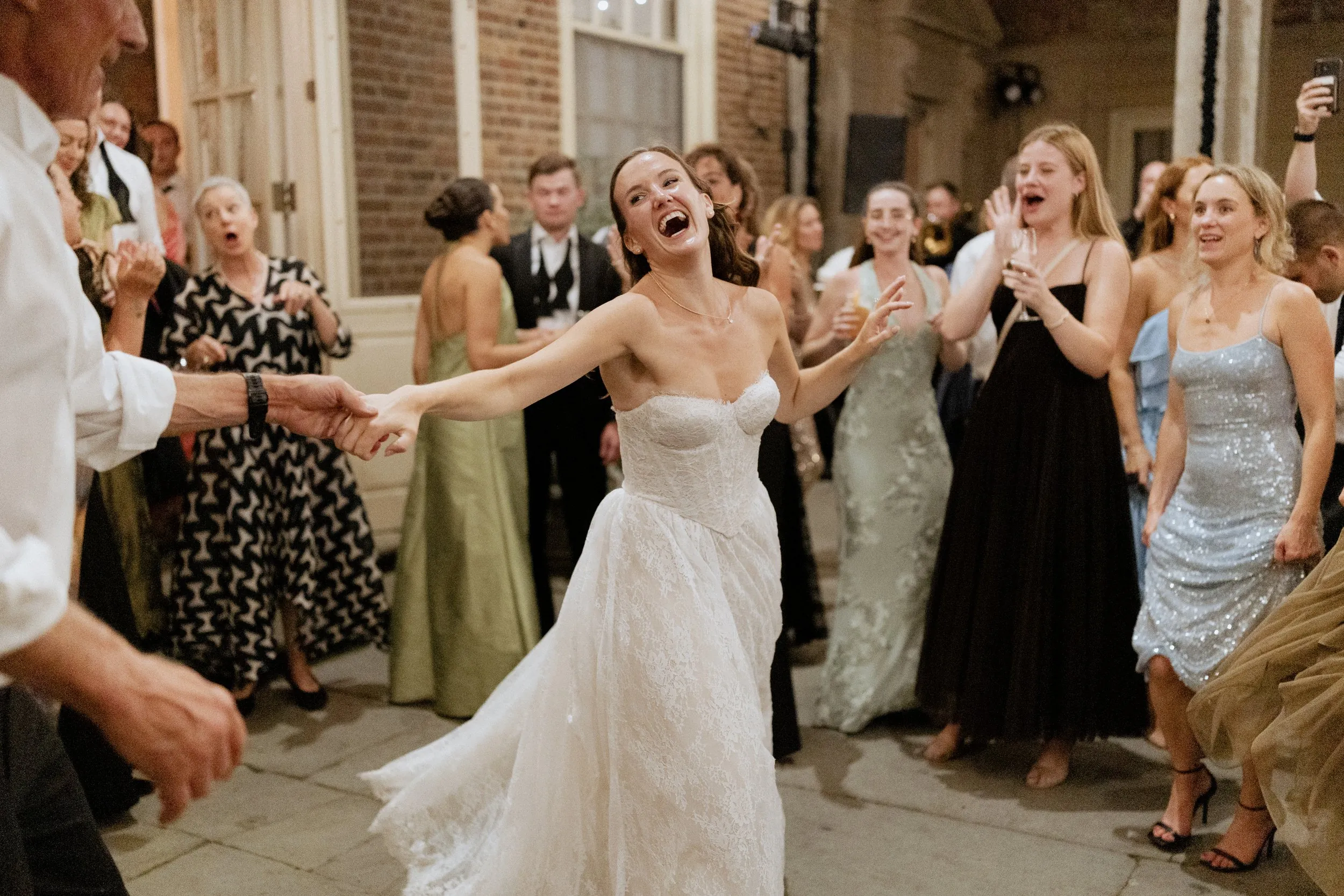 Bride laughing mid-spin surrounded by guests at the end of the night