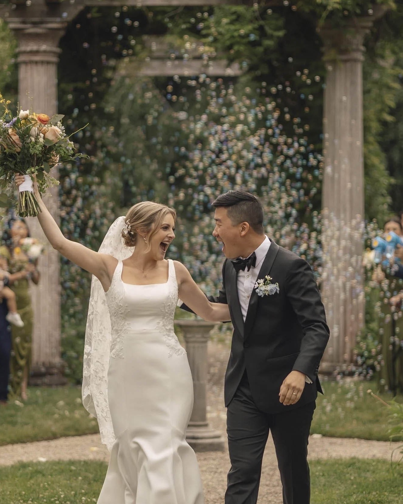 A couple laughs through a bubble exit after a garden ceremony in Sarasota