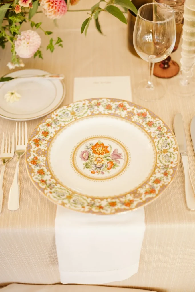 A floral-patterned china plate, printed menu and wine glass on a white place setting at a Hill-Stead Museum wedding reception