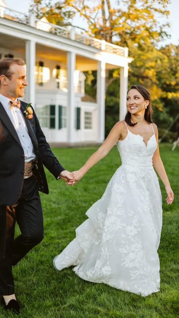 Bride and groom hold hands walking across the lawn beside the white house at Hill-Stead Museum in late-afternoon light, Farmington, CT