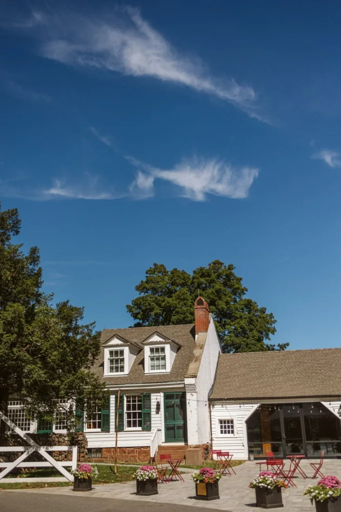 The shingled entrance building and flower boxes at Hill-Stead Museum in Farmington, CT under a blue summer sky