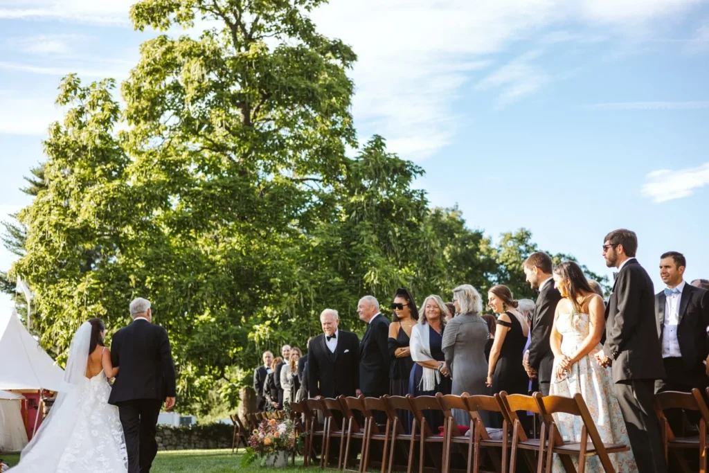 Bride walks down the grass aisle on her father's arm past standing guests at a Hill-Stead Museum wedding ceremony, Farmington, CT
