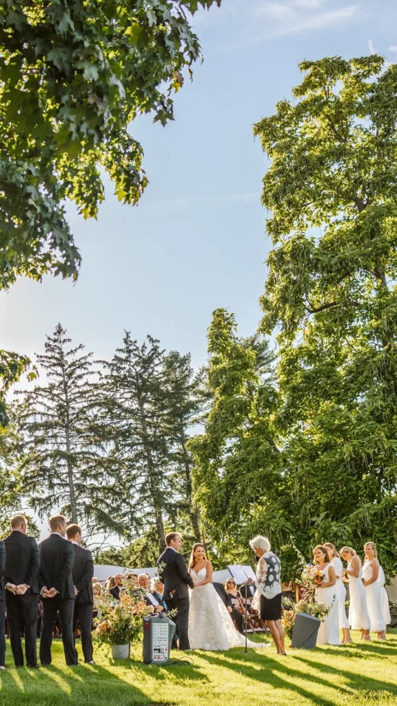Tall vertical view of the West Lawn ceremony at Hill-Stead Museum framed by the big trees overhead