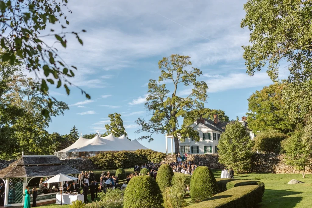Looking down over the Sunken Garden hedges at Hill-Stead Museum to cocktail hour guests, the sailcloth tent and the house beyond, Farmington, CT