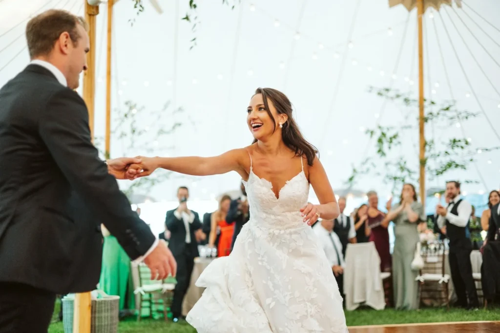 Groom leads the bride onto the dance floor for their first dance under the tent at Hill-Stead Museum as guests applaud