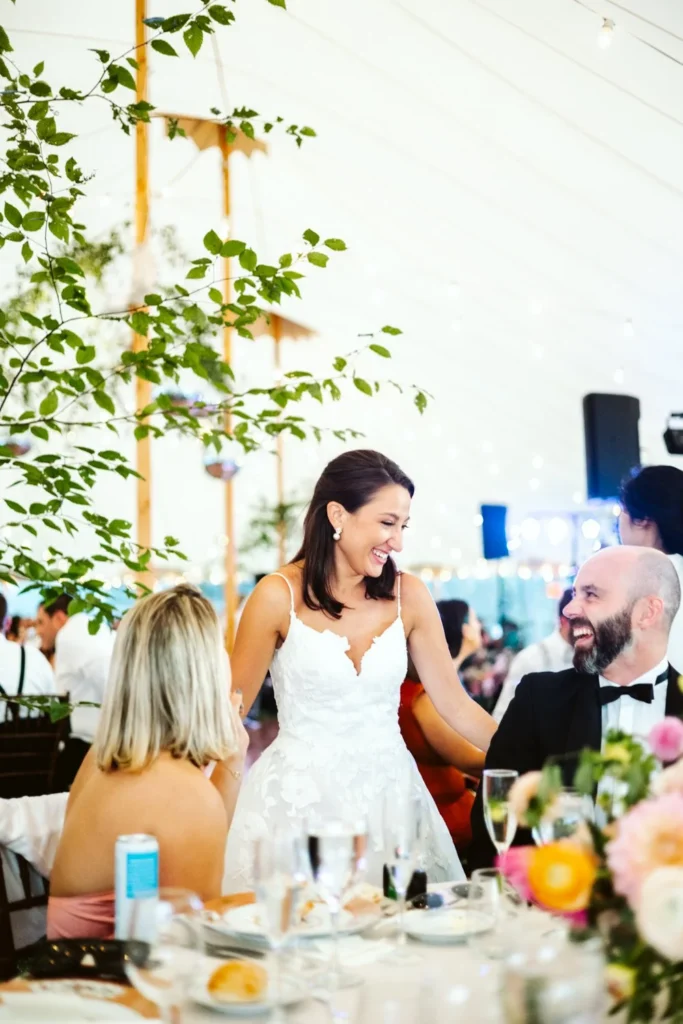 Bride and groom laugh with guests at a dinner table under the tent at Hill-Stead Museum
