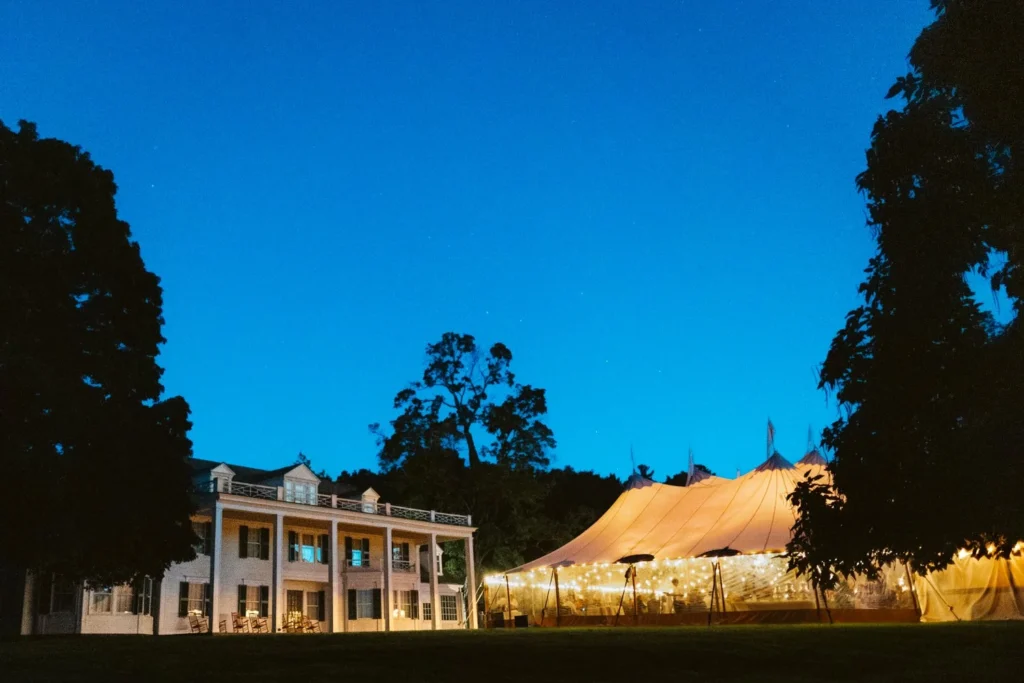 The Hill-Stead Museum house and a glowing sailcloth tent on the West Lawn under a deep blue evening sky, Farmington, CT