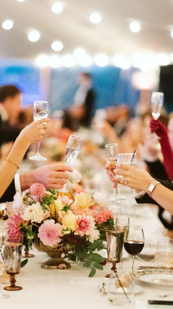 Guests raise champagne glasses over a dahlia centerpiece under string lights at a Hill-Stead Museum wedding
