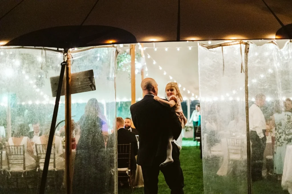 A parent dance seen through the clear tent wall and string lights at Hill-Stead Museum after dark