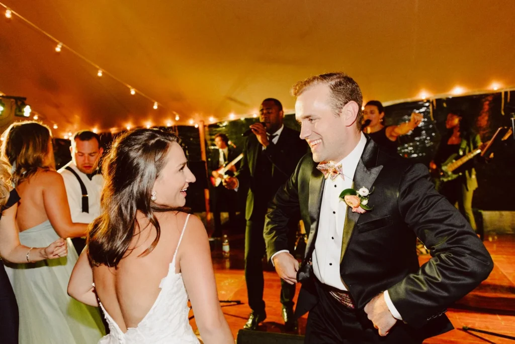 Bride and groom laugh together on the dance floor in front of the band under the tent at Hill-Stead Museum