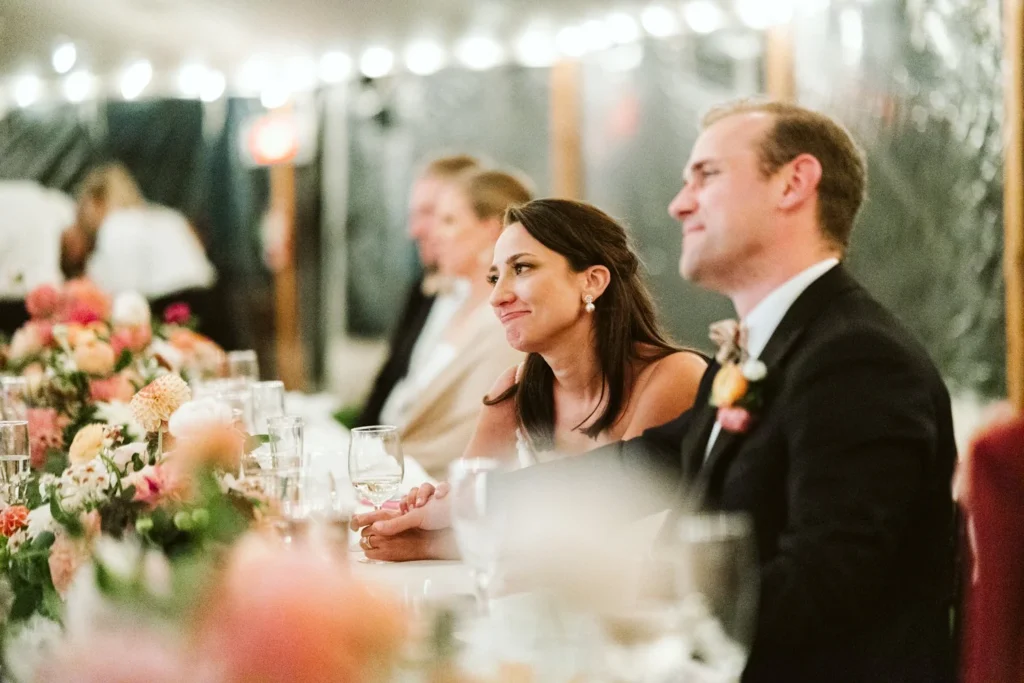 Bride and groom react to a toast at the head table under the tent at Hill-Stead Museum