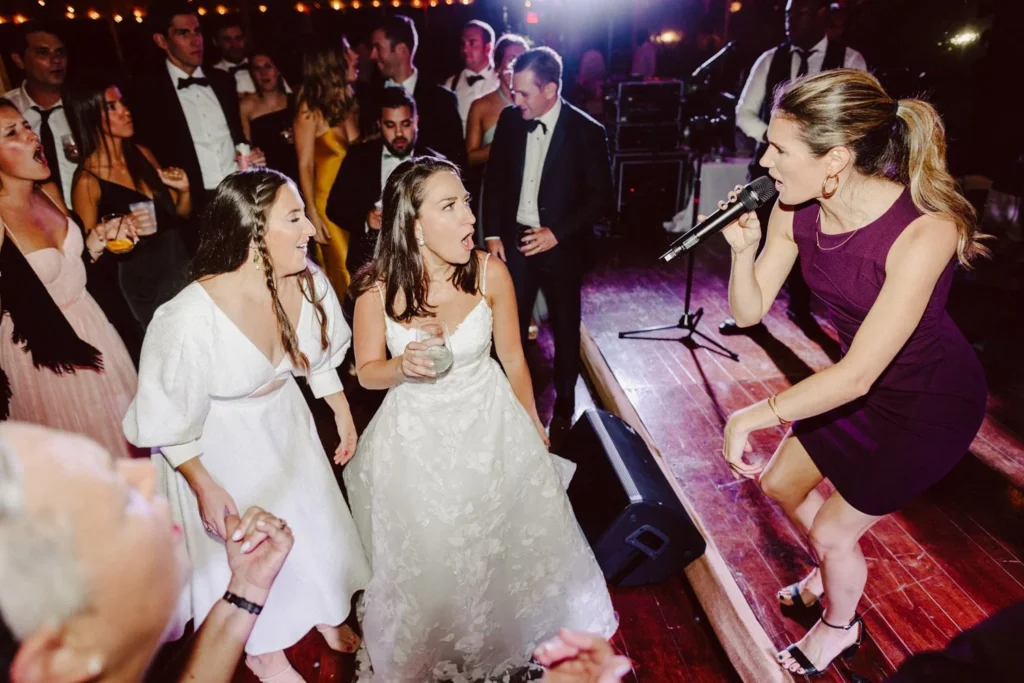 A band singer performs from the stage to dancing wedding guests under string lights inside the tent at Hill-Stead Museum
