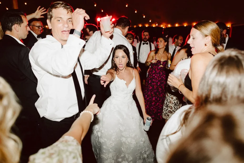 Bride dances in the middle of the crowd under string lights at Hill-Stead Museum
