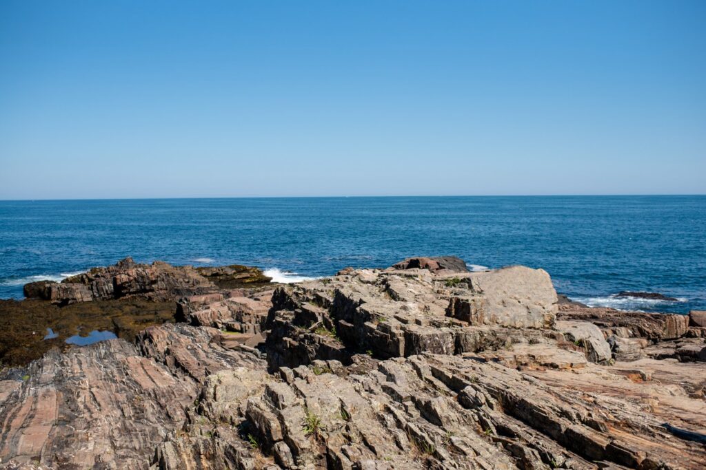 Layered granite ledges at the base of Bald Head Cliff below Cliff House Maine with the Atlantic Ocean breaking on the rocks