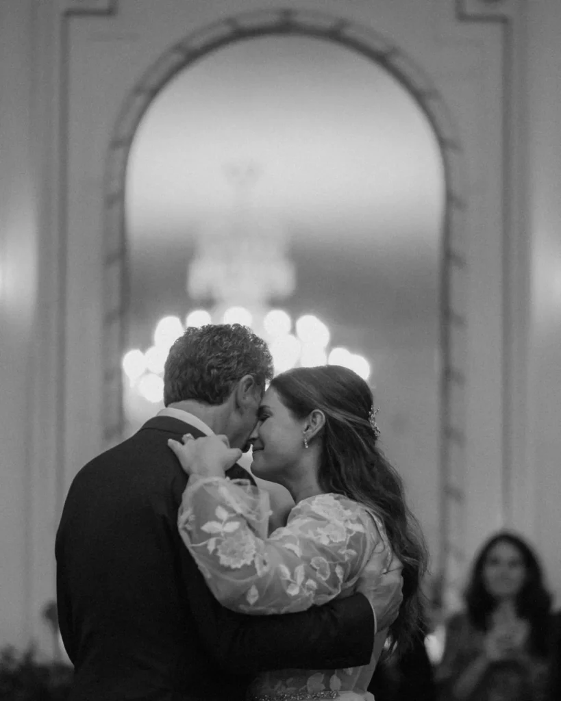 Black and white photo of the first kiss at an indoor wedding ceremony in the Tupper Manor ballroom