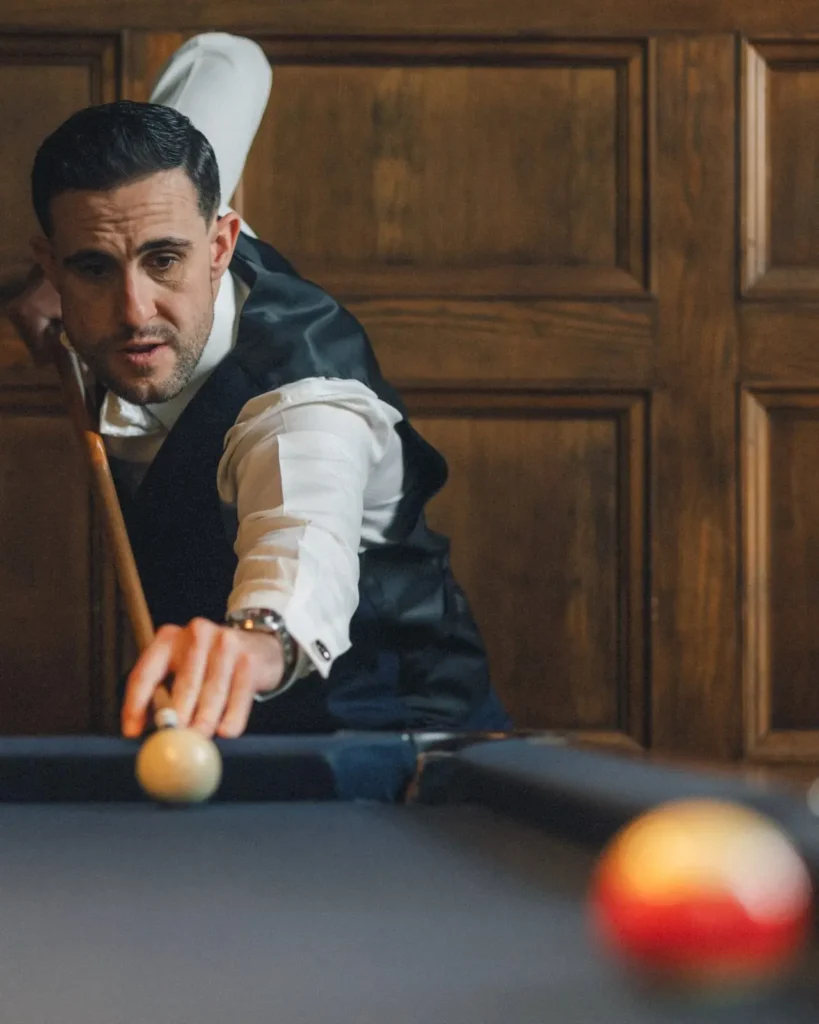 Groomsman lines up a pool shot in the billiards room at Tupper Manor before the wedding