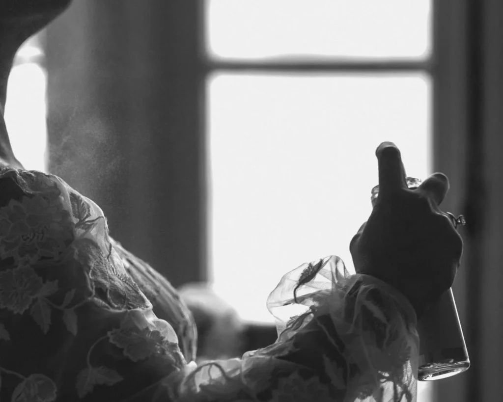 Black and white photo of the bride adjusting her hair in window light in the getting-ready suite at Tupper Manor