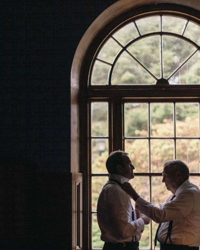 Two guests embrace by the arched window inside Tupper Manor during cocktail hour