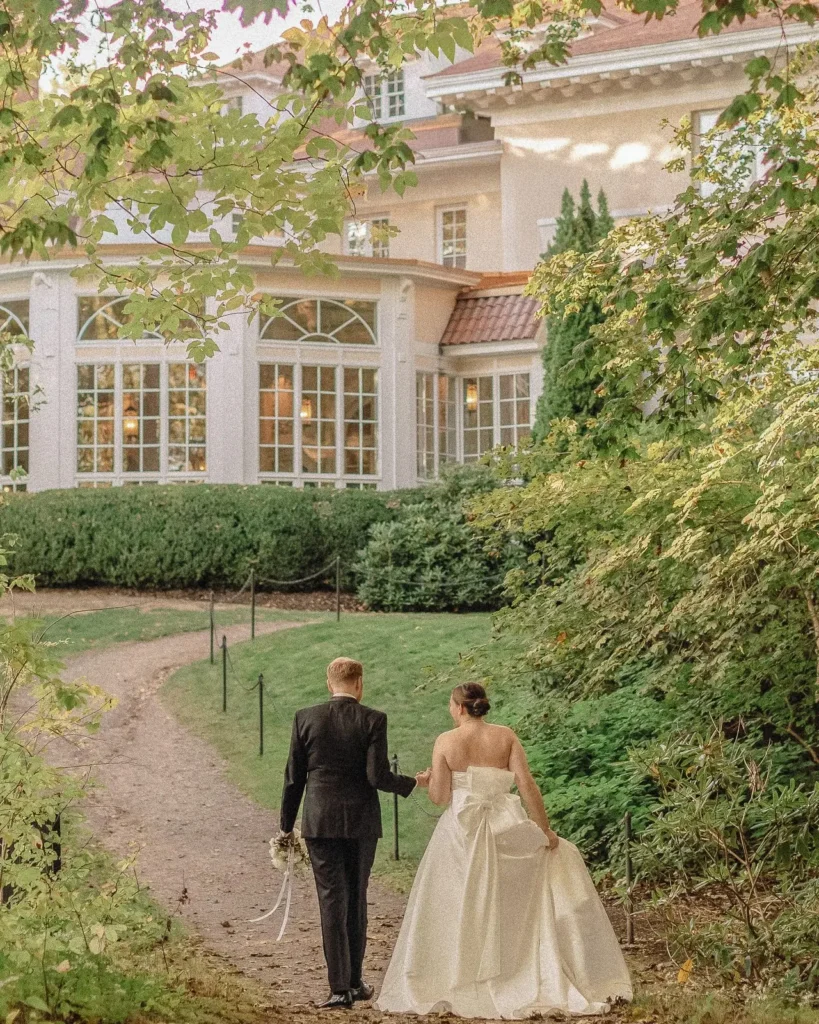 Bride and groom walk the garden path back toward Tupper Manor after their first look
