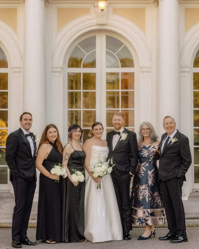 Bride and groom with their families in front of the arched windows at Tupper Manor