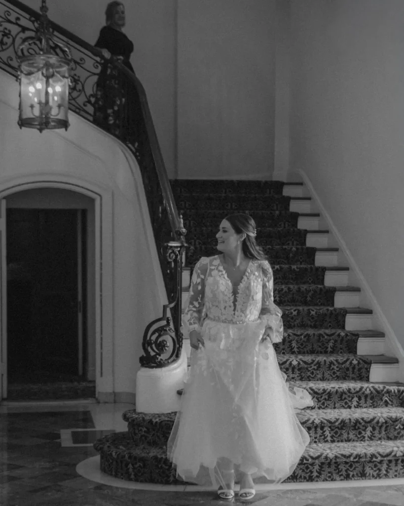 Bride descends the grand staircase into the marble foyer at Tupper Manor in black and white