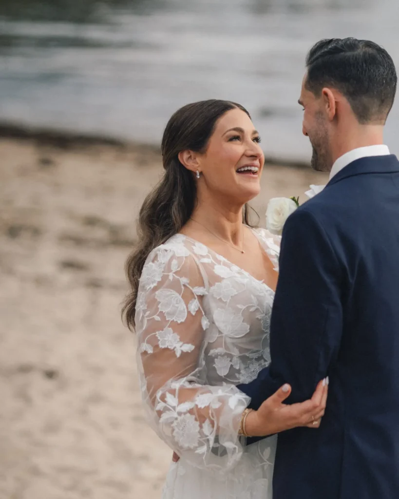 Bride laughing with the groom on the private beach below Tupper Manor in Beverly, MA