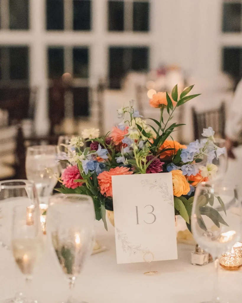 Colorful floral centerpiece and table number at a Tupper Manor wedding reception
