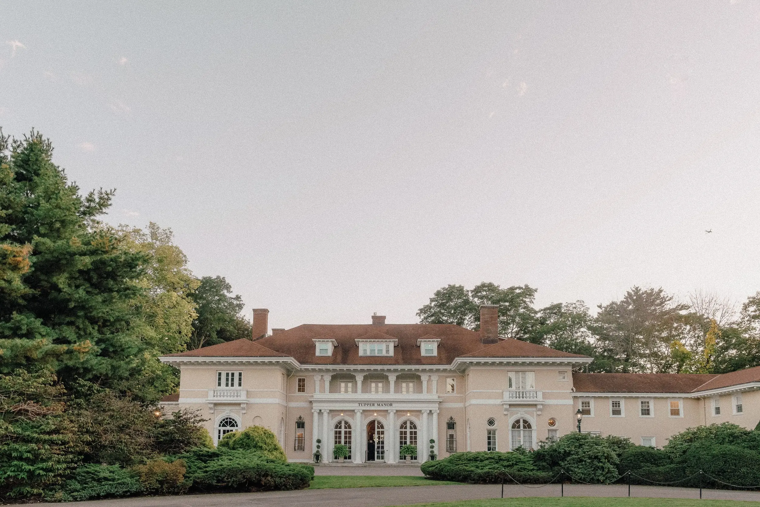 Tupper Manor Wedding 1 Tupper Manor, the 1901 Georgian mansion wedding venue in Beverly, MA, seen across the front lawn at dusk